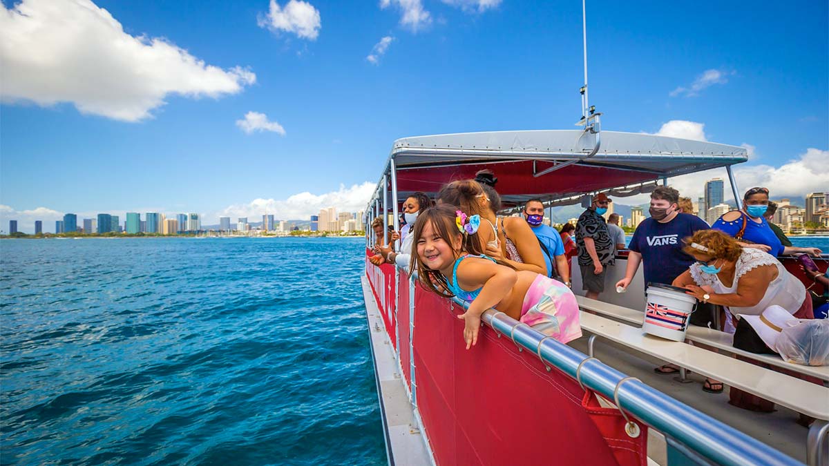 a photo of the people, both adults and kids, inside a red sailing boat.